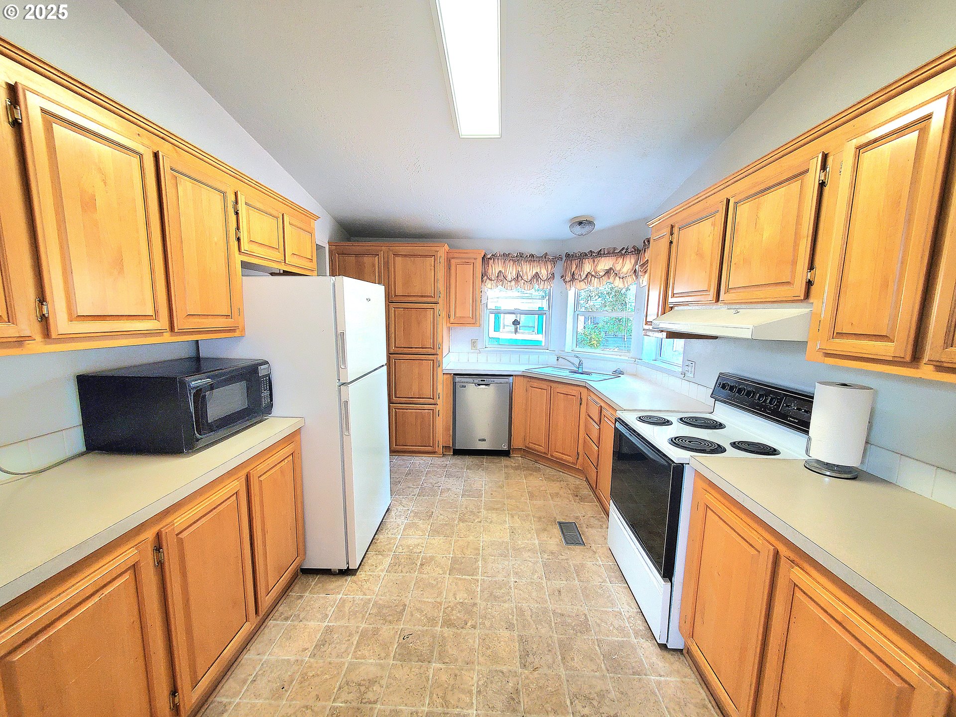 1125 58th Street, Unit 6 Springfield, OR 97478 - Photo 4 of 27 a kitchen with stainless steel appliances a refrigerator sink and wooden cabinets