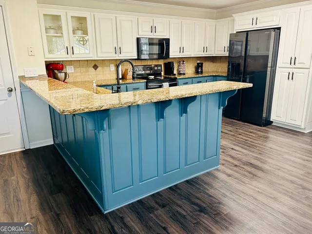 a kitchen with kitchen island granite countertop wooden cabinets a refrigerator and a sink