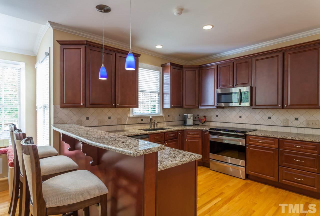 2408 Wertherson Lane Raleigh, NC 27613 - Photo 4 of 25 a kitchen with stainless steel appliances granite countertop wooden cabinets a dining table and chairs