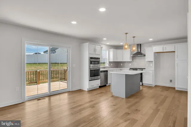 a large kitchen with a large counter top a sink stainless steel appliances and cabinets