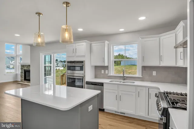 a kitchen with stainless steel appliances granite countertop a sink a stove and a wooden floors