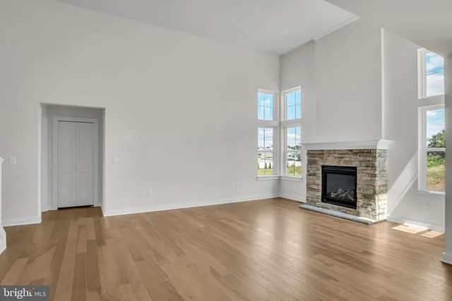 an empty room with wooden floor fireplace and windows