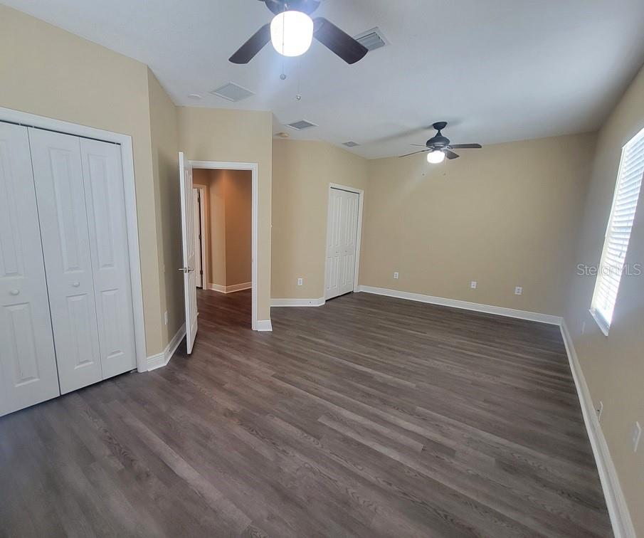 10418 Fenceline Road New Port Richey, FL 34655 - Photo 31 of 36 an empty room with wooden floor chandelier fan and windows