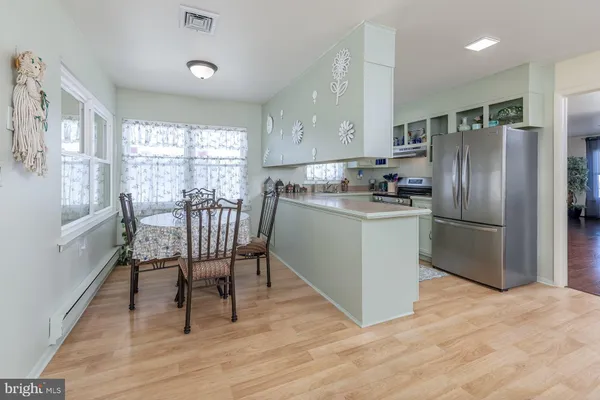 a kitchen with stainless steel appliances granite countertop a table chairs refrigerator and microwave