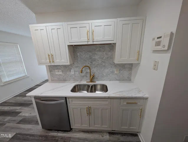 a kitchen with white cabinets a sink and dishwasher