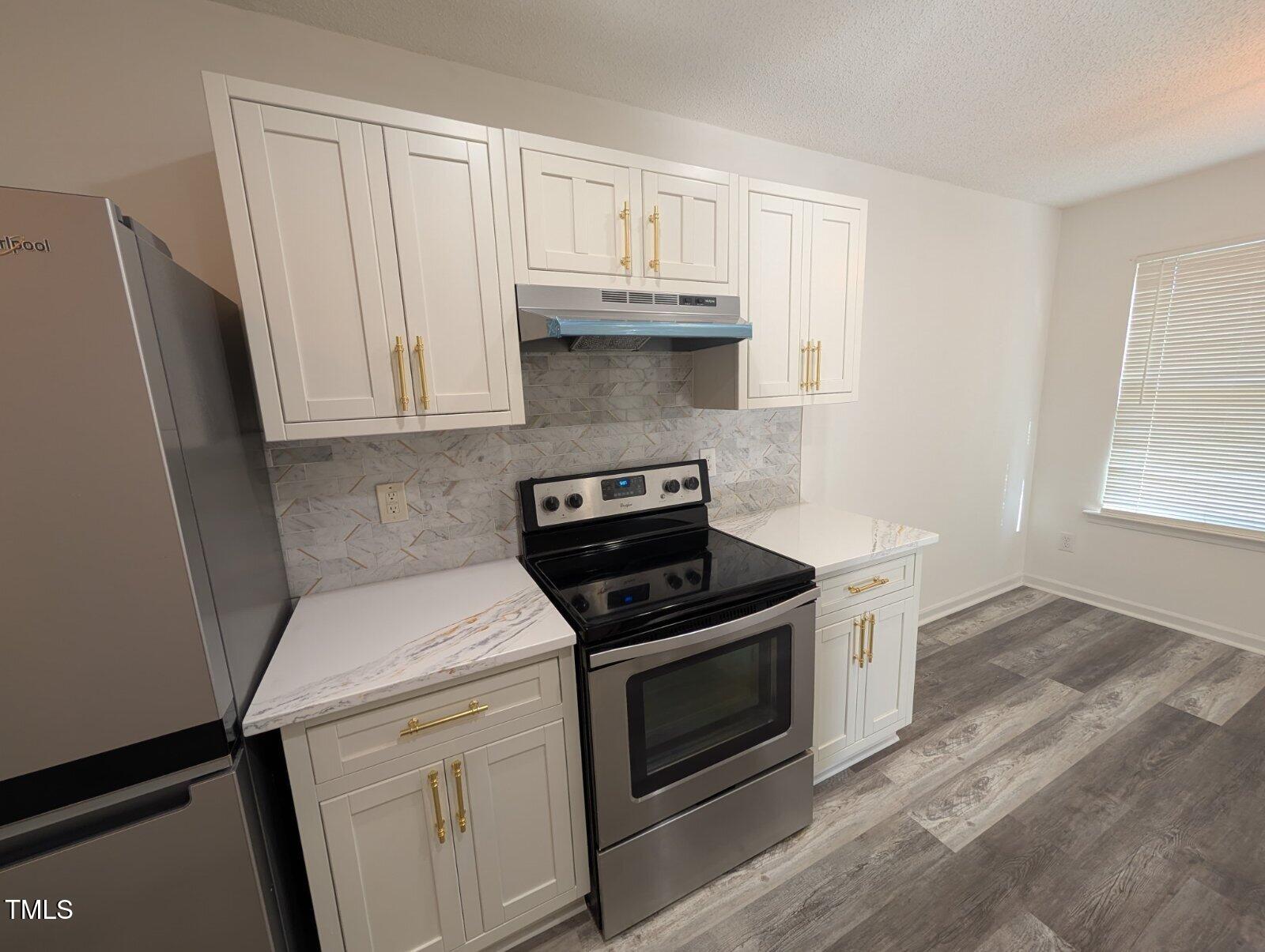 7528 Argent Valley Drive Raleigh, NC 27616 - Photo 18 of 47 a kitchen with white cabinets and black appliances