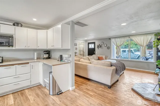 a living room with stainless steel appliances granite countertop furniture and a wooden floor