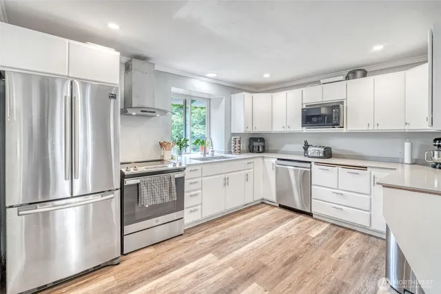 a kitchen with white cabinets stainless steel appliances and window