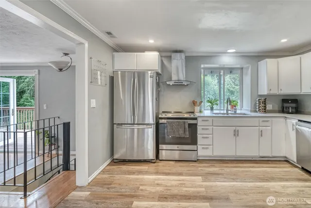 a kitchen with granite countertop a refrigerator oven a sink and white cabinets