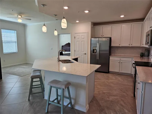 a kitchen with stainless steel appliances granite countertop a sink a stove a refrigerator cabinets and chairs