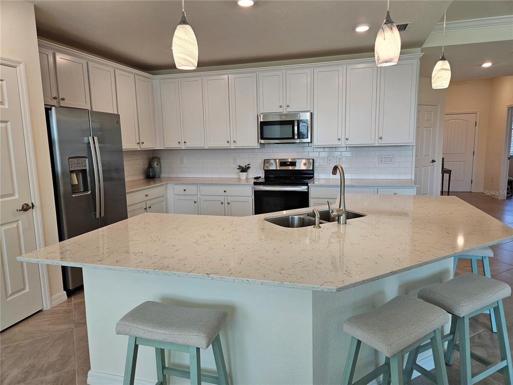 10039 Crooked Creek Drive, Unit 102 Venice, FL 34293 - Photo 16 of 36 a kitchen with stainless steel appliances granite countertop a sink a stove a refrigerator cabinets and chairs