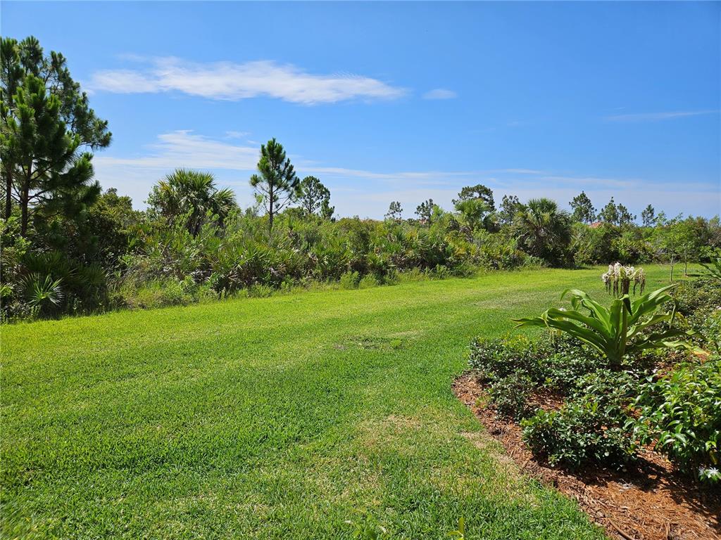 10039 Crooked Creek Drive, Unit 102 Venice, FL 34293 - Photo 20 of 36 a view of a garden with a tree in the background