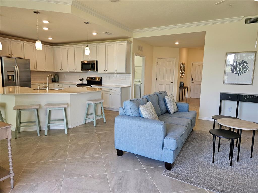 10039 Crooked Creek Drive, Unit 102 Venice, FL 34293 - Photo 23 of 36 a living room with stainless steel appliances kitchen island granite countertop furniture and a view of kitchen