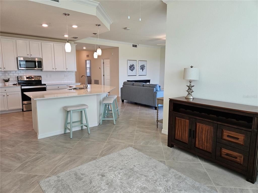 10039 Crooked Creek Drive, Unit 102 Venice, FL 34293 - Photo 25 of 36 a kitchen with kitchen island granite countertop a sink counter top space appliances and cabinets
