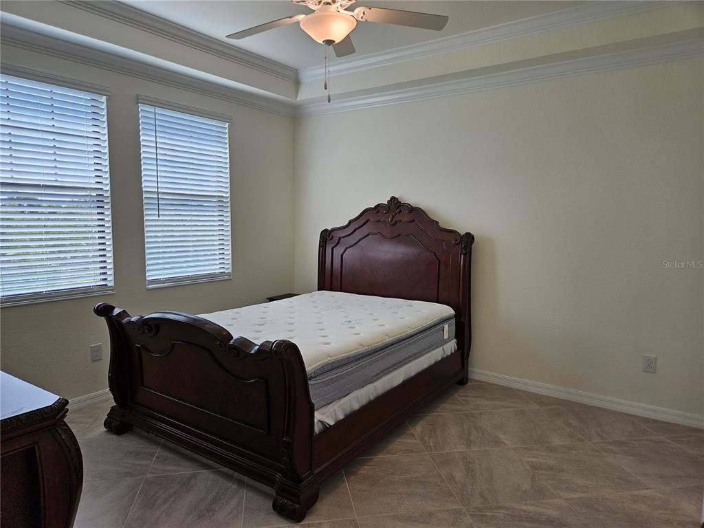 10039 Crooked Creek Drive, Unit 102 Venice, FL 34293 - Photo 26 of 36 a bed sitting in a bedroom next to a window and a chandelier