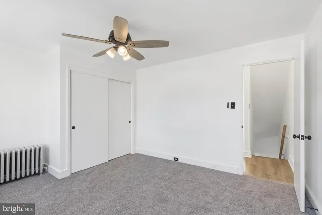 an empty room with a fan & a window
