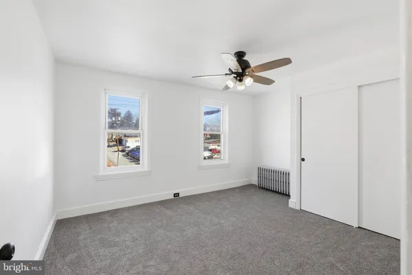 an empty room with a fan & a window