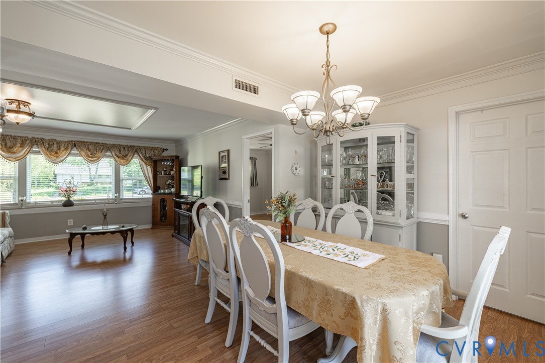 9217 Fisk Road Richmond, VA 23229 - Photo 16 of 39 a dining room with wooden floor a chandelier a wooden table and chairs