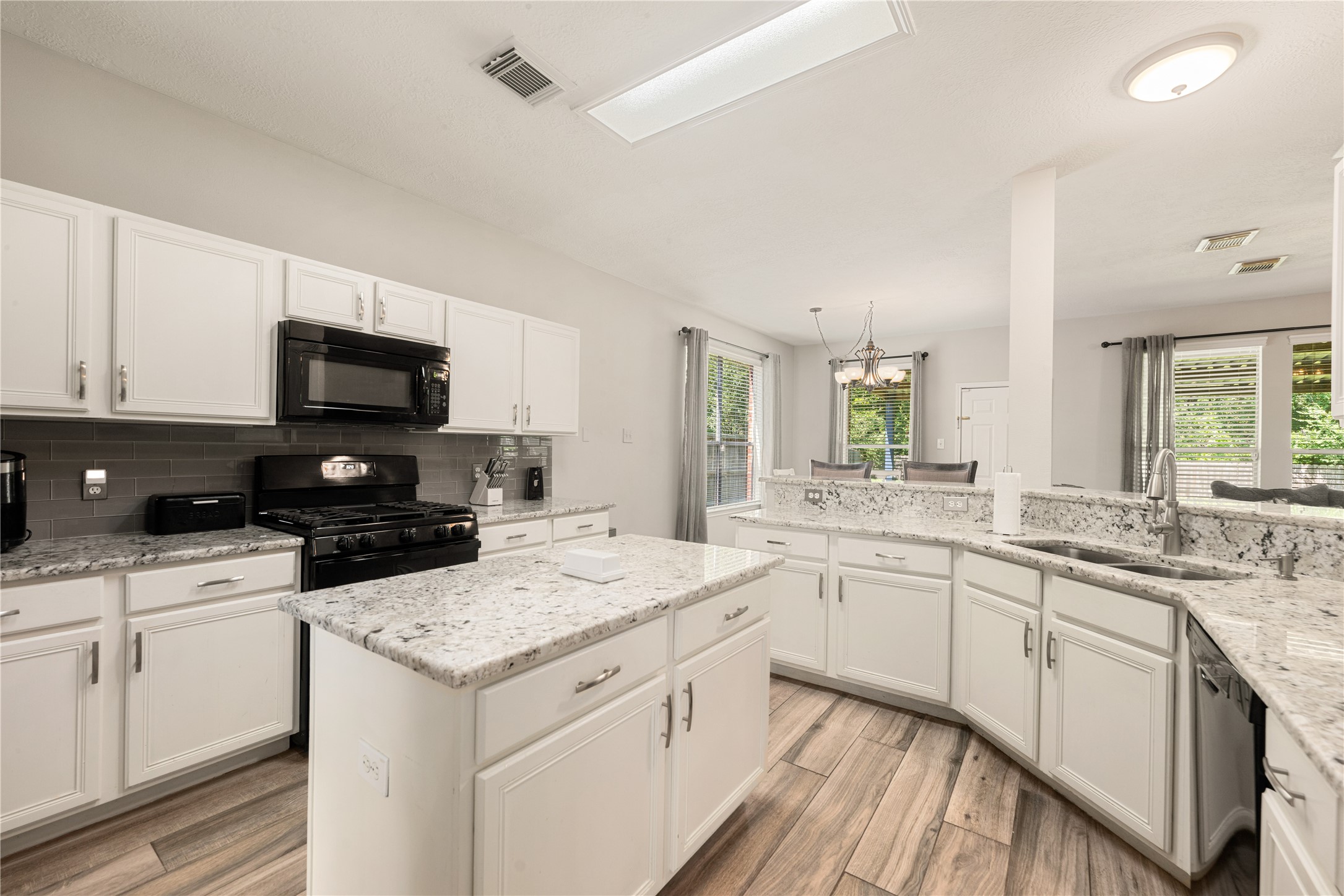 19726 Teller Boulevard Spring, TX 77388 - Photo 8 of 24 The heart of this space is a generous central island, perfect for morning coffee or casual meal prep. Stunning stone-patterned countertops wrap around crisp white cabinetry, providing a sophisticated look and an abundance of storage.