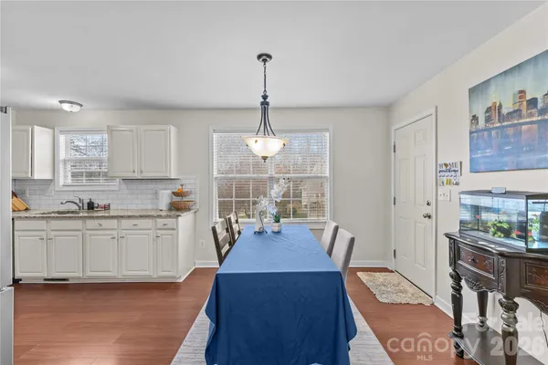a view of a dining room and livingroom with furniture wooden floor a rug and a chandelier
