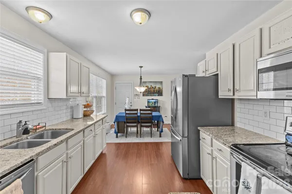 a kitchen with granite countertop a refrigerator stove and sink