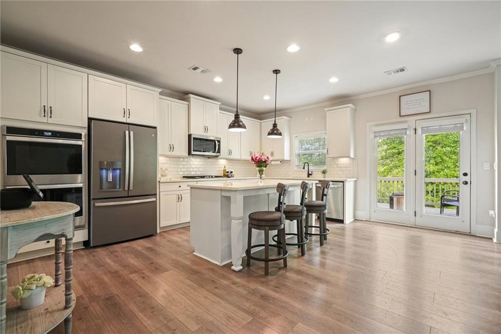 6915 Rambling Vale Dawsonville, GA 30534 - Photo 14 of 63 a kitchen with stainless steel appliances kitchen island granite countertop a refrigerator a stove a sink a dining table and chairs with wooden floor