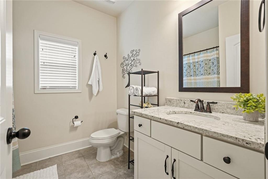 6915 Rambling Vale Dawsonville, GA 30534 - Photo 22 of 63 a bathroom with a granite countertop toilet sink and mirror