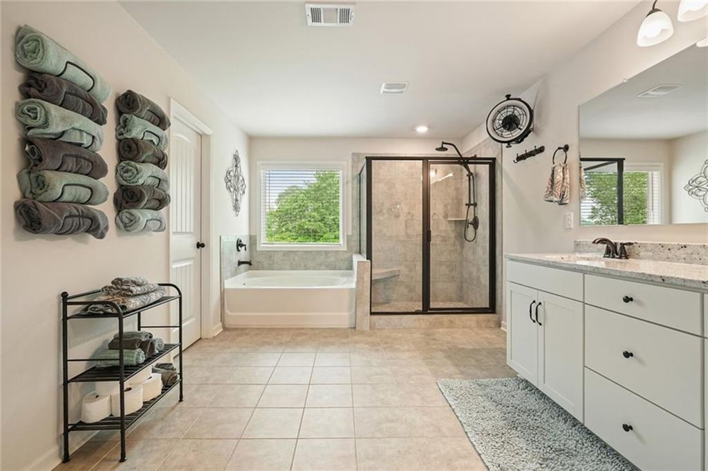 6915 Rambling Vale Dawsonville, GA 30534 - Photo 39 of 63 a spacious bathroom with a granite countertop sink a mirror and a bathtub