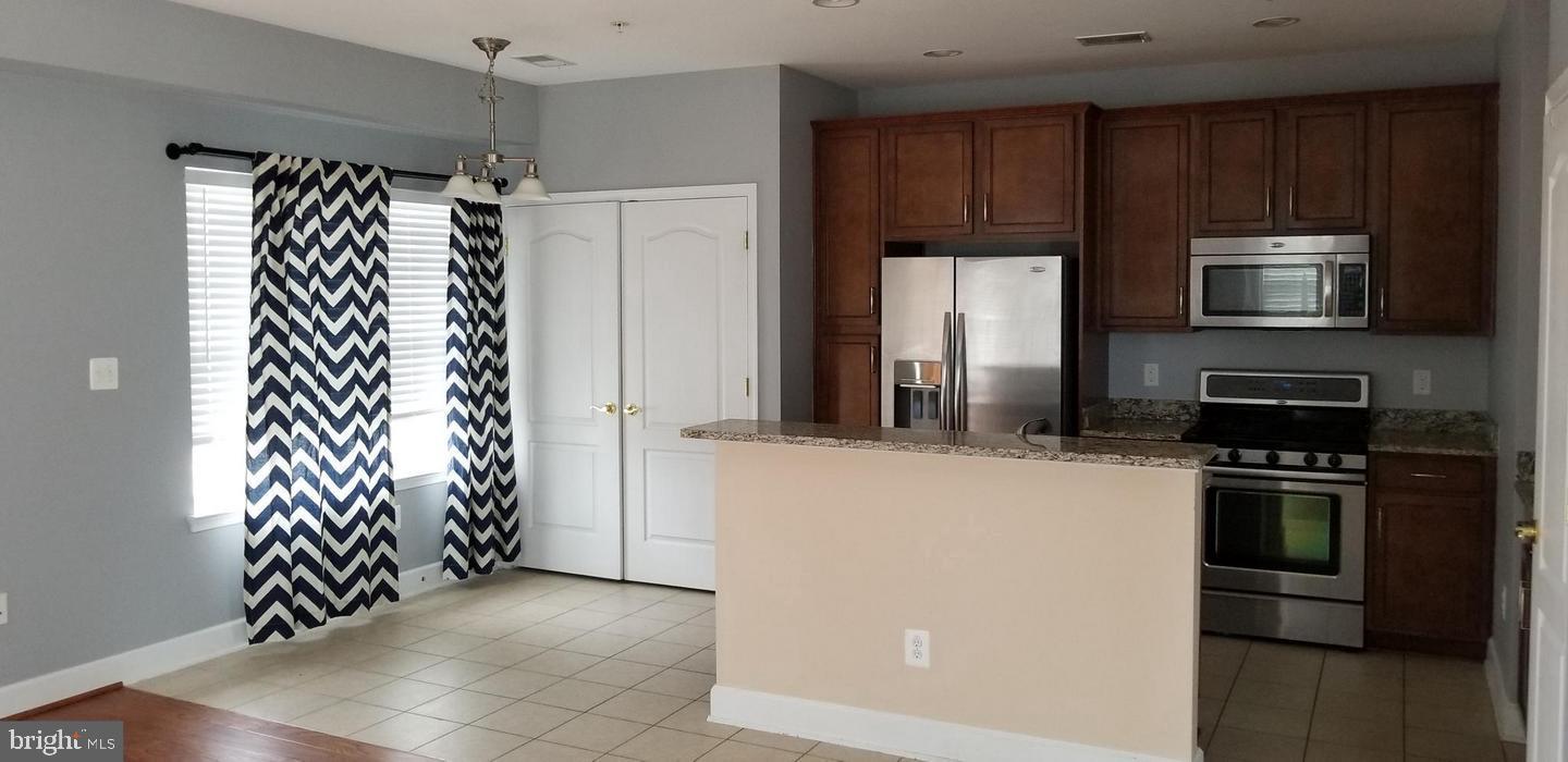 13595 Station Street Germantown, MD 20874 - Photo 2 of 7 a kitchen with granite countertop a refrigerator and a stove top oven