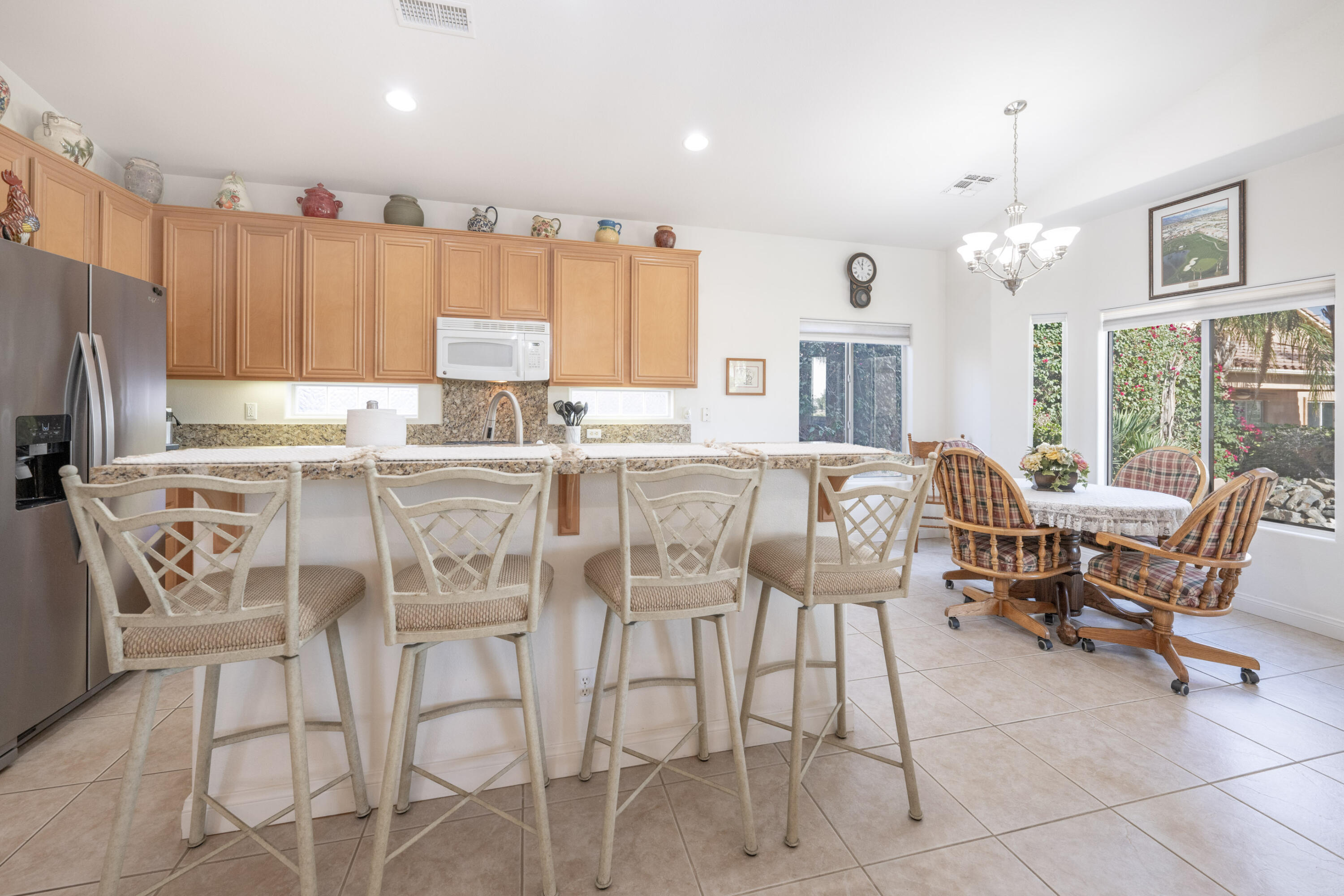45138 Banff Springs Street Indio, CA 92201 - Photo 26 of 38 a kitchen with stainless steel appliances kitchen island granite countertop a stove a refrigerator a sink a dining table and chairs