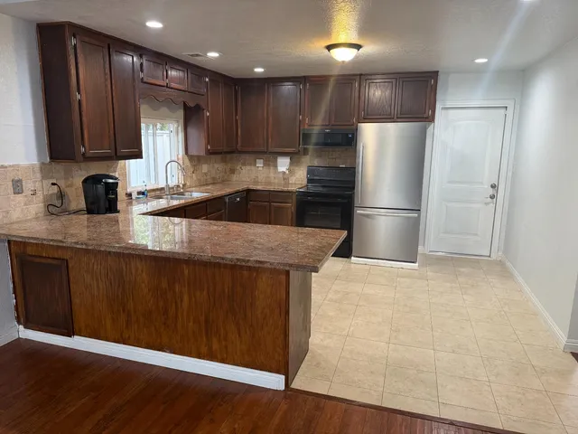 a kitchen with stainless steel appliances granite countertop a refrigerator a sink a stove a microwave and wooden cabinets