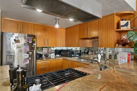 a kitchen with stainless steel appliances granite countertop a table chairs and a living room view