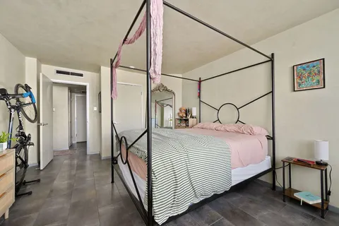 a bedroom with a bed a flat screen tv and windows