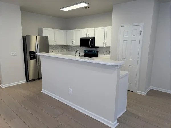 a view of a kitchen with a refrigerator a microwave and cabinets