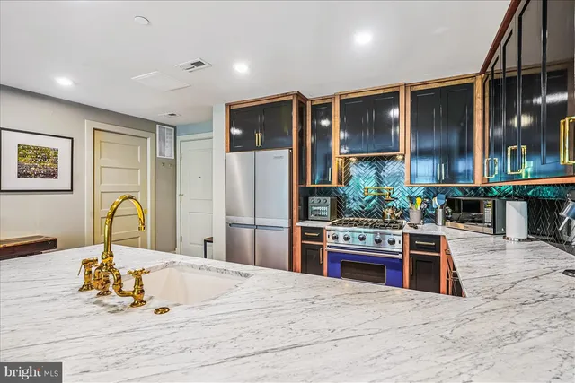 a kitchen with stainless steel appliances kitchen island granite countertop a refrigerator a stove and a sink with wooden floor