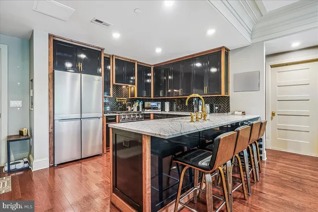 a kitchen with stainless steel appliances granite countertop wooden floor a refrigerator and wooden cabinets