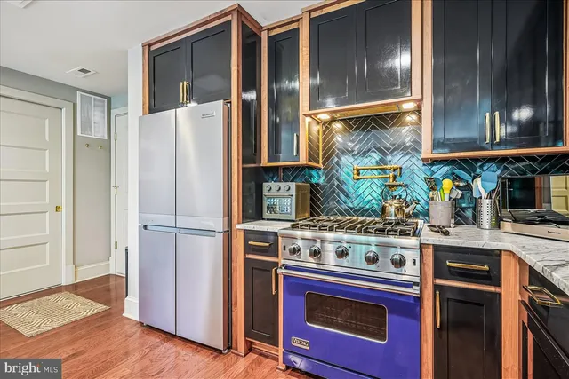 a kitchen with stainless steel appliances granite countertop a refrigerator a stove and a wooden floors