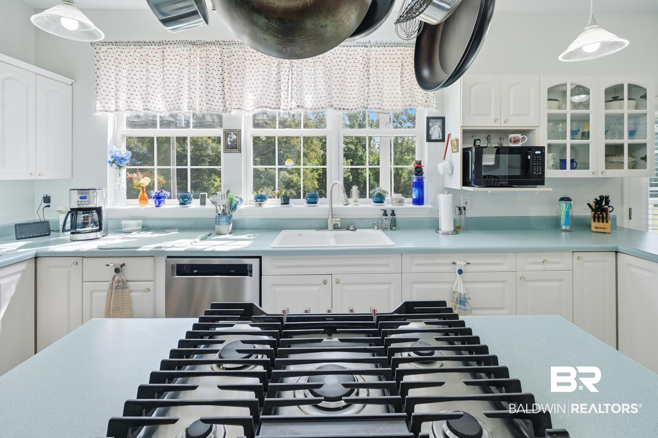 15855 Calvin Richerson Road Bay Minette, AL 36507 - Photo 29 of 83 Kitchen featuring white cabinetry with glass-front accents, a central island with an integrated gas cooktop, and light blue countertops