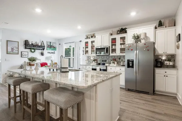 a kitchen with a dining table chairs cabinets and wooden floor