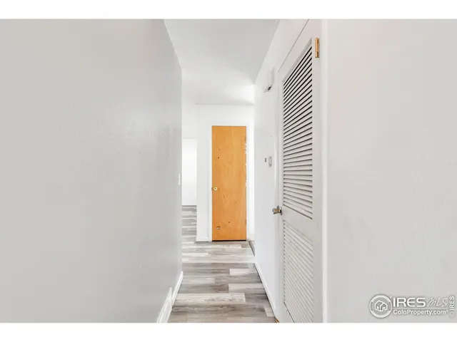 a view of a hallway with wooden floor and a bathroom