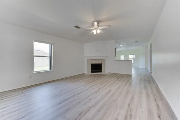 an empty room with wooden floor fireplace and windows