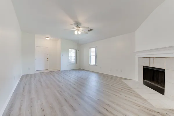 a view of empty room with wooden floor and fireplace