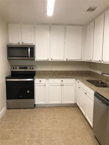 a kitchen with granite countertop white cabinets and stainless steel appliances