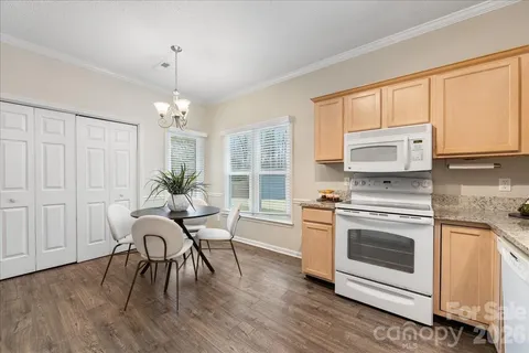 a kitchen with stainless steel appliances a stove a sink a refrigerator cabinets and a dining table