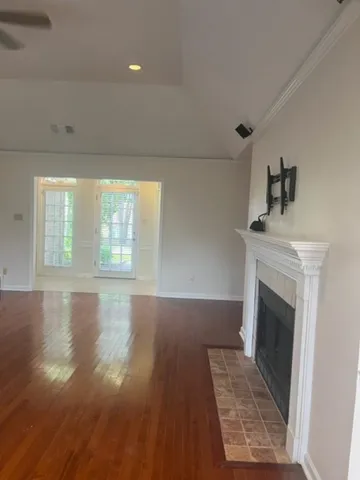 a view of an empty room with wooden floor fireplace and a window