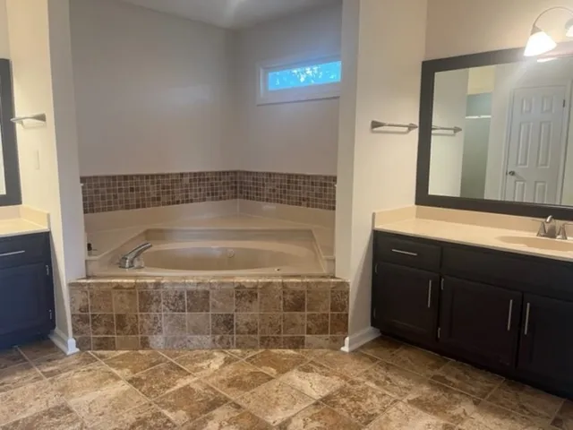 a bathroom with a granite countertop sink a mirror and shower
