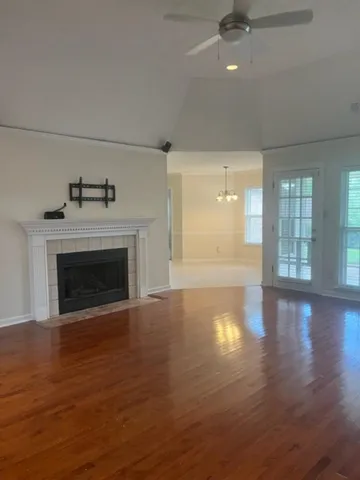 an empty room with wooden floor fireplace and windows