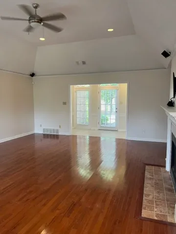 an empty room with wooden floor fan and windows