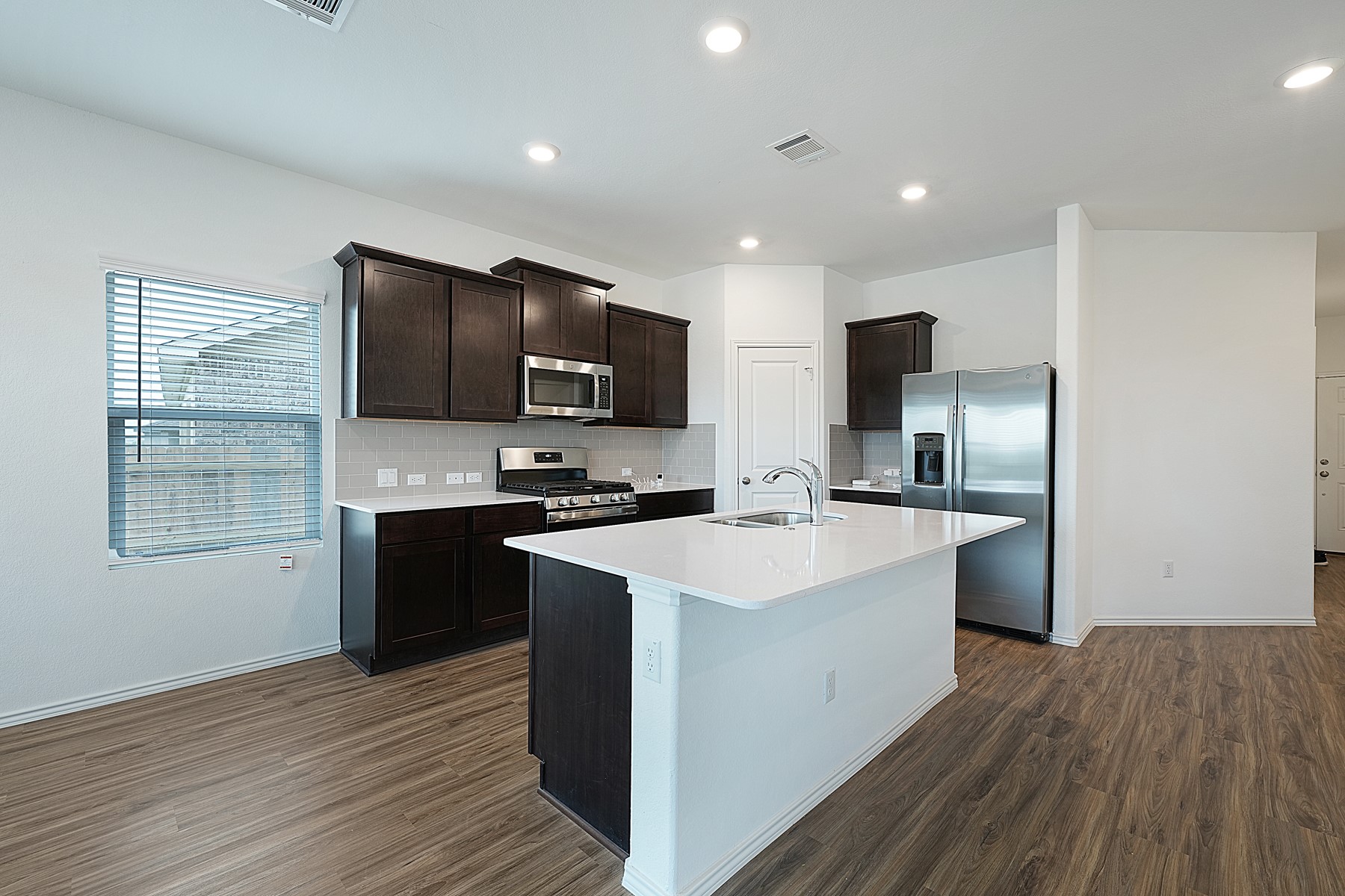 932 Mallow Road Leander, TX 78641 - Photo 20 of 34 A contemporary kitchen showcasing dark wood cabinetry, stainless steel appliances, and an inviting island with a sink.