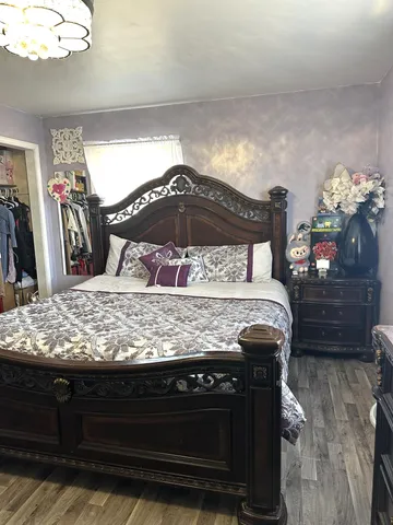 a bedroom with a bed a chandelier and dresser